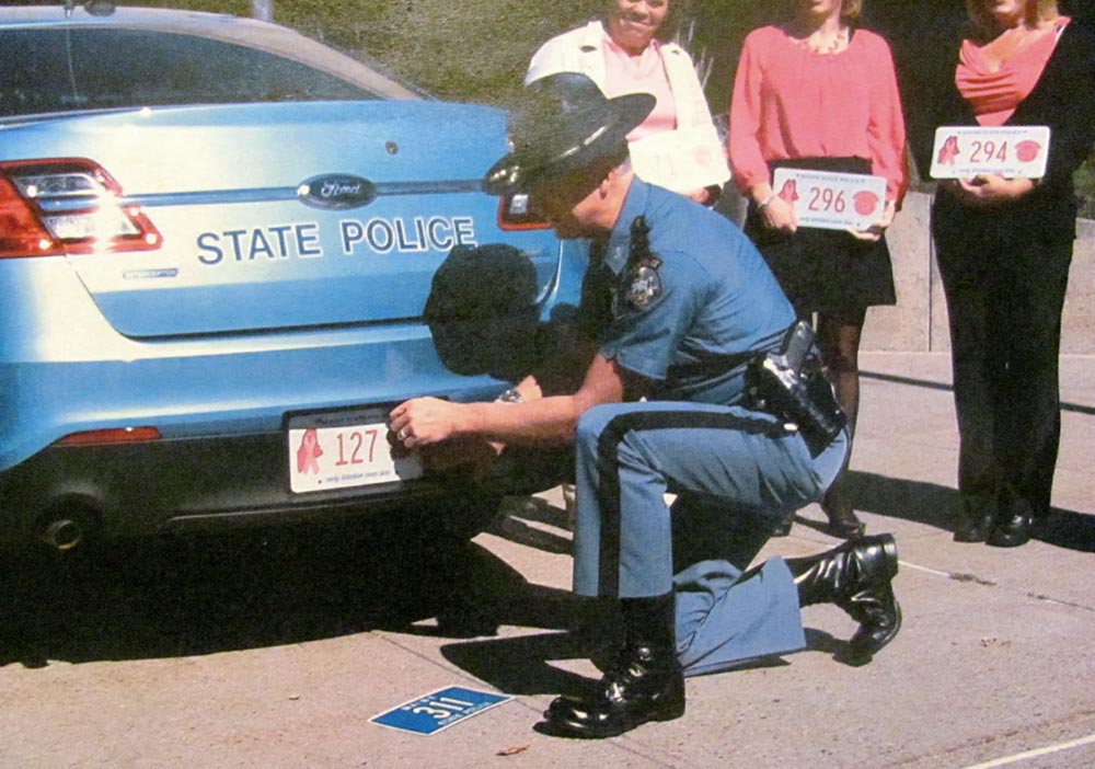 Maine police officer changing license plate on police car